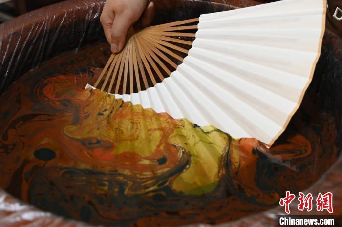 4月18日,漂漆扇制作,张曼瑜将白色扇面放入水中进行漂染。张俊杰 摄