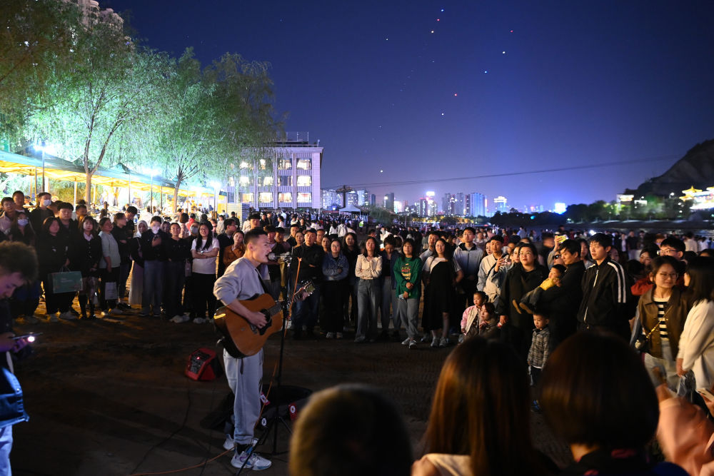 4月23日，在兰州市城关区的黄河兰州段近水平台，市民及游客观看音乐爱好者弹唱。新华社记者　范培珅　摄