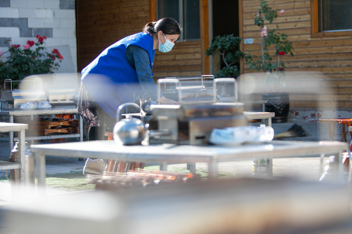 图为一名社区工作者在淄博市高青县田镇街道帮助烧烤摊主摆放餐具。（新华社发 张维堂 摄）