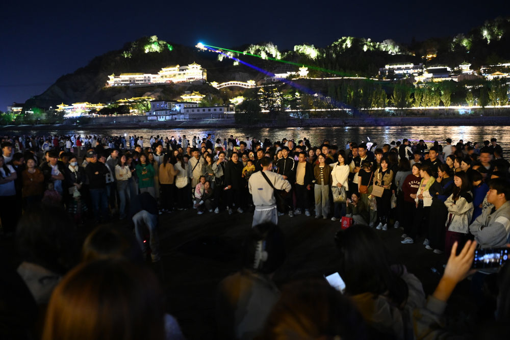 4月23日，在兰州市城关区的黄河兰州段近水平台，市民及游客观看音乐爱好者弹唱。新华社记者　范培珅　摄