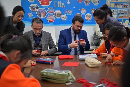 ▲ 4月22日，法国欧坦市市长一行来到朝阳小学，和师生一起学习剪纸。记者 梅耀 摄