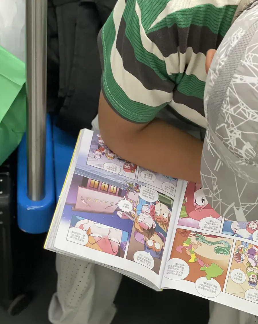 2023年8月22日，刚刚旅行回京的一家三口，小朋友在看一本名叫《甘肃寻宝记》的漫画书。