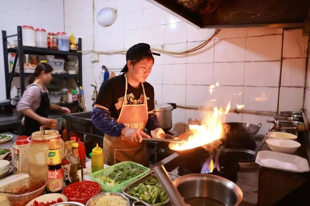 王细军在后厨炒菜。周建红/摄