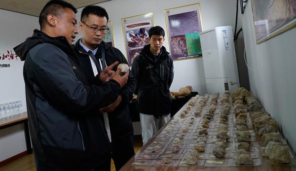 考古队员卢龙涛（左一）向记者介绍发掘出的石核石器