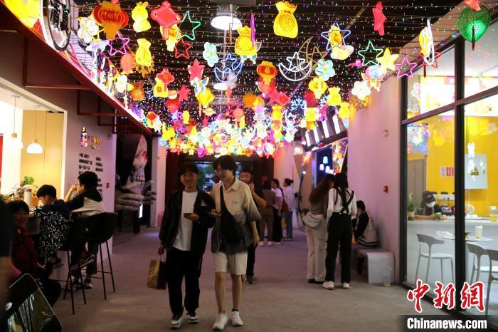 5月2日，在山东临沂新琅琊不夜街区，游客在彩灯下走过。　孙磊 摄