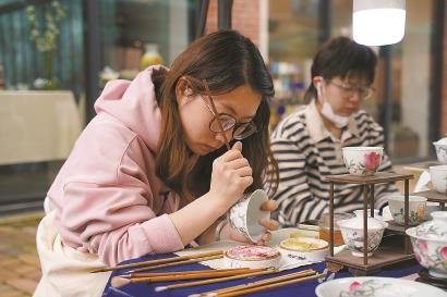 ▲陶溪川市集的绿伞传统区,一位创作者在瓷器上作画。 王倩 摄