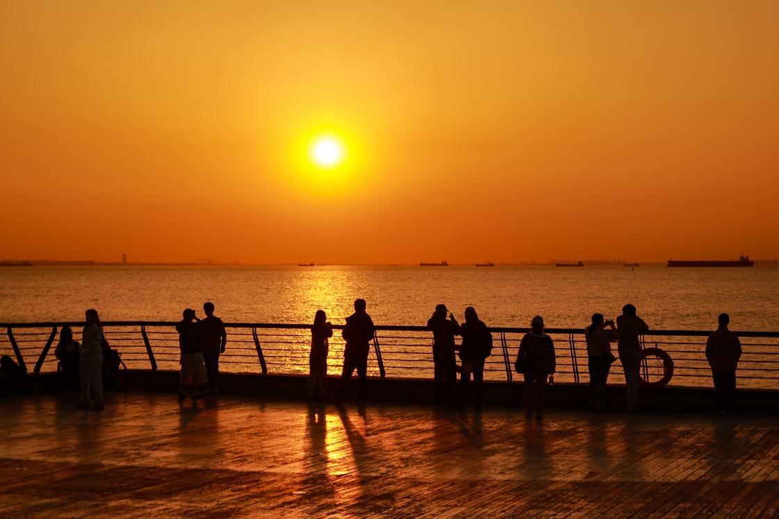 游客在金茂湾后海广场欣赏海上日落 