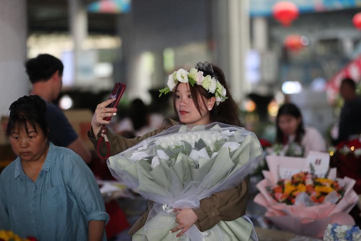 昆明斗南花卉交易市场内，游客正在抱着花束拍照打卡。（受访者供图）