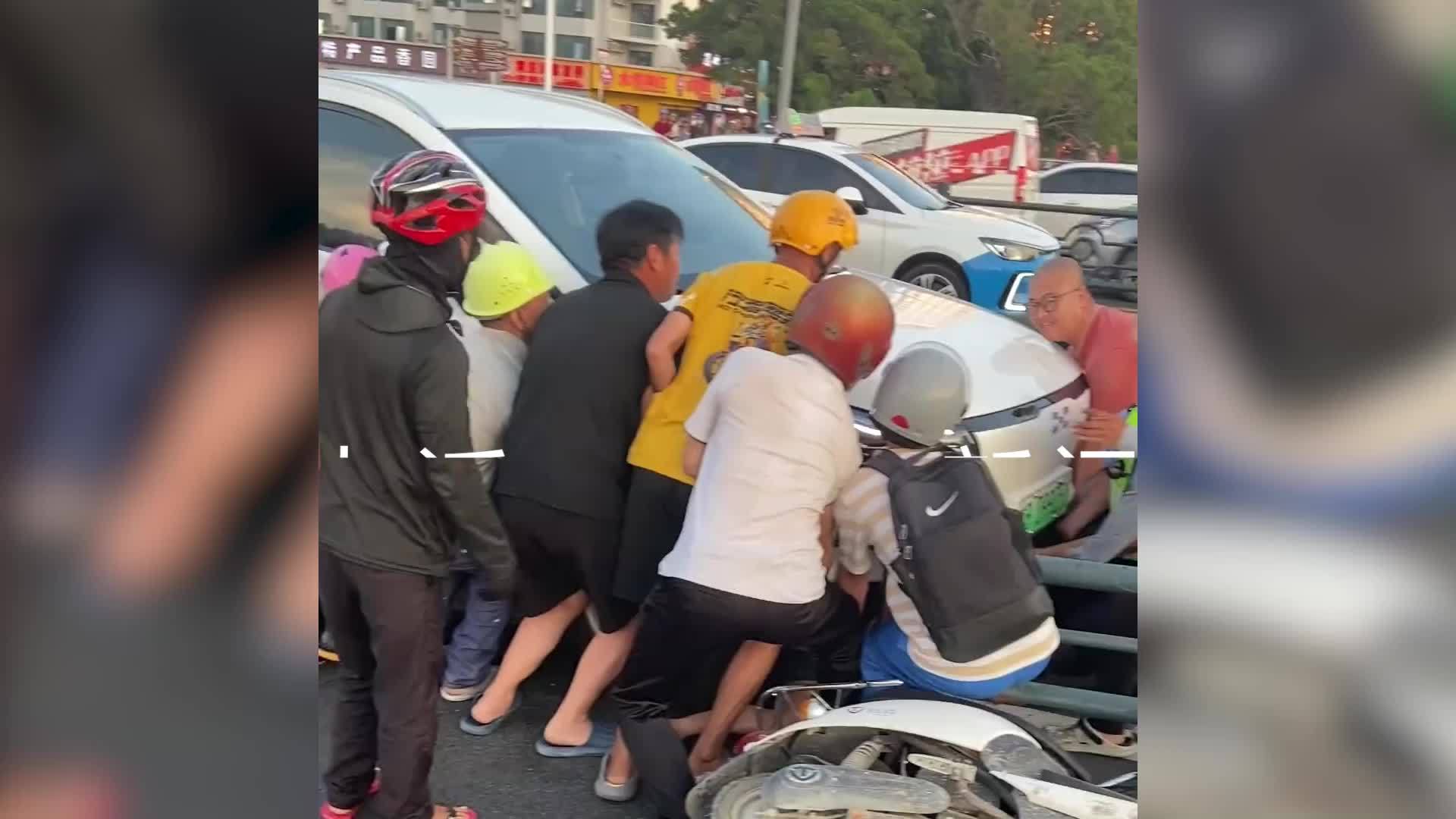 三亚群众路遇车祸合力抬车救人参与者人群从车头排至车尾