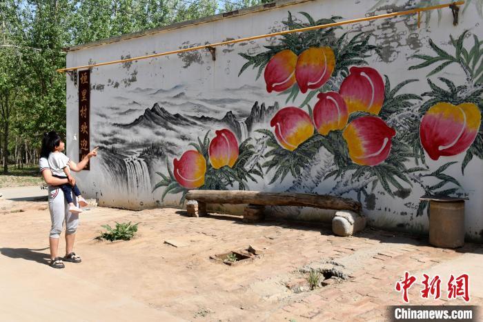 5月13日，深州市王家井镇垣里村，村民观看李培芝所画的墙体画。刘娟 摄