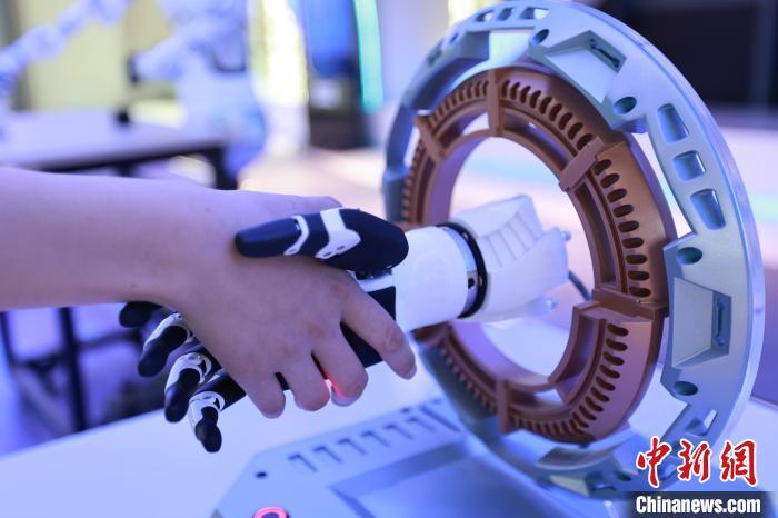 5月16日,在位于河北省邯郸市邯山区的邯郸人工智能教育基地,游客正在与仿生机械手进行握手。 李昊 摄