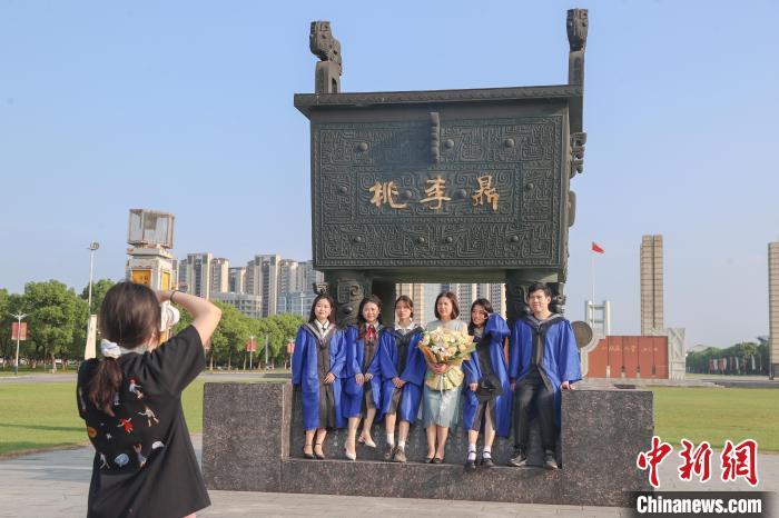 图为江西师范大学2024届毕业生和自己的老师一起在学校标志性建筑桃李鼎前拍照留念。刘力鑫 摄
