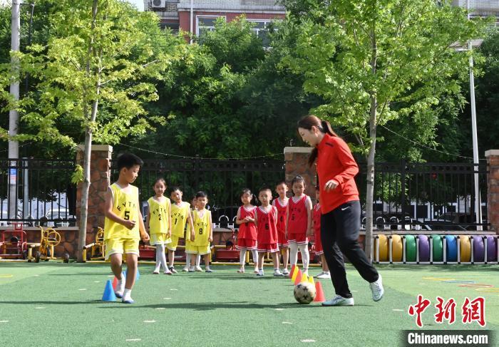 5月16日，河北省保定市育德幼儿园，2016中国女子足球甲级联赛冠军贾向宁(右一)指导孩子们练习足球。中新网记者 翟羽佳 摄