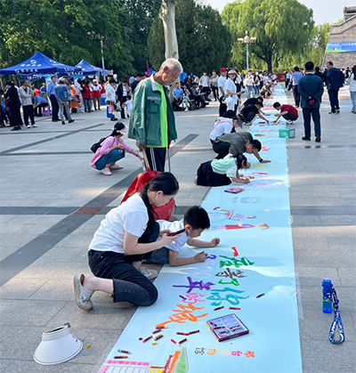 5月9日，在全国共青团为老志愿服务和助残志愿服务现场会上，孩子和家长认真为百米画卷涂色。