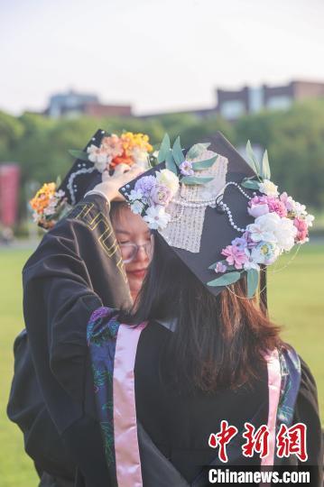 图为一位江西师范大学2024届毕业生在拍照前帮助同伴整理学位帽。刘力鑫 摄