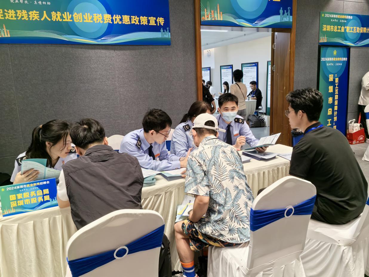 图说：在税惠助残政策宣传专区，税务干部为纳税人缴费人解答税费政策问题，辅导个税APP汇算操作