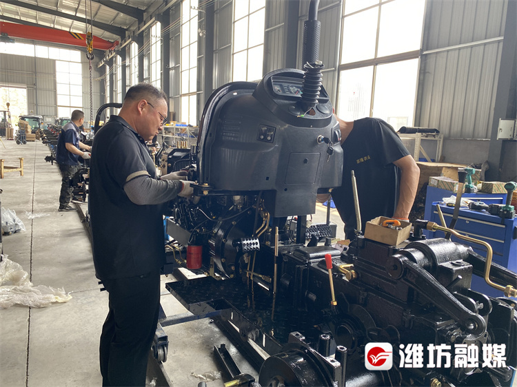 潍坊朗派国际贸易有限公司生产车间内，工人在组装农用拖拉机底盘。