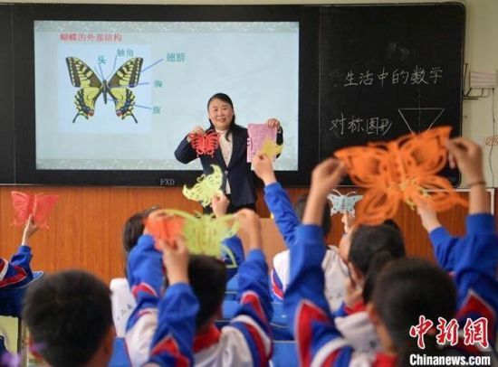 王雪娟老师用剪纸艺术启发学生们理解数学的轴对称图形概念。刘栋 摄