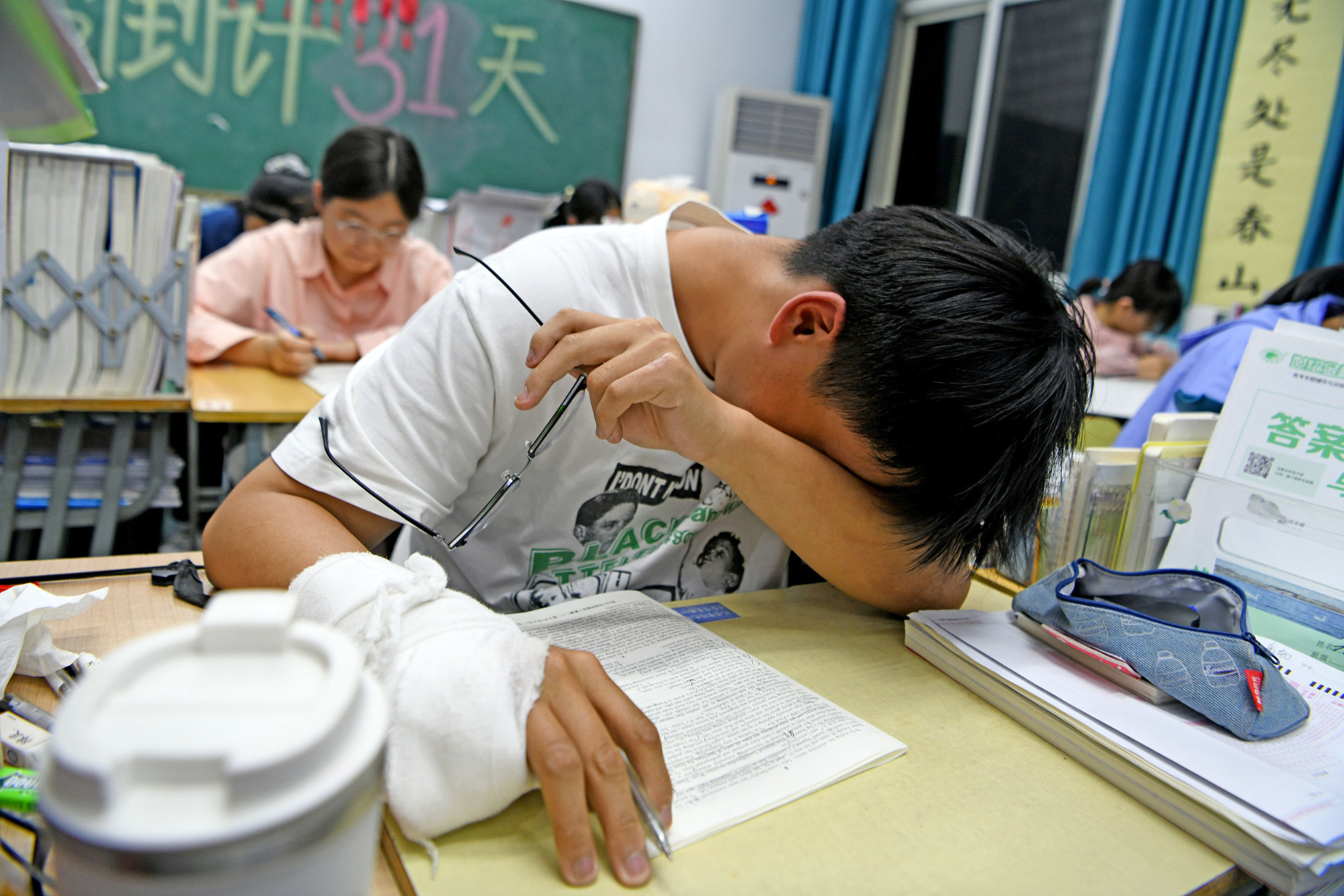 2024年5月7日，安徽省淮南市一中，一名手部受伤的高三学生在晚自习课堂上做题。