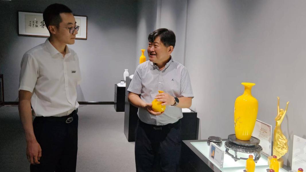孙云毅（右）向齐商银行客户经理介绍鸡油黄琉璃产品