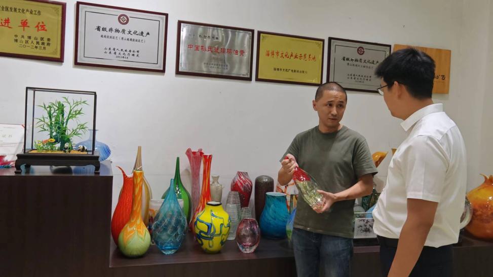 孙云浩（左）向齐商银行客户经理介绍琉璃产品