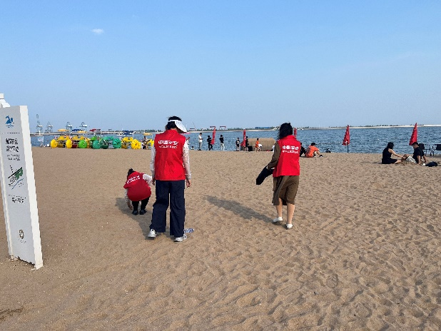 图片介绍：志愿者在沙滩捡拾垃圾