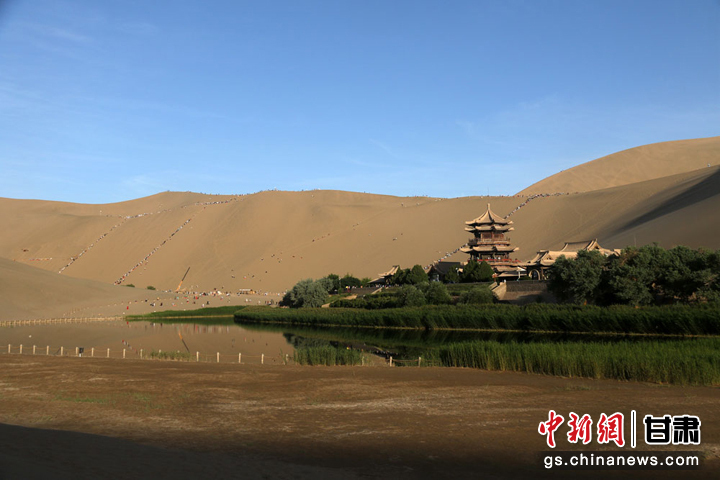 6月9日，游客在敦煌市鸣沙山月牙泉景区游览。