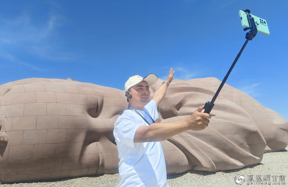 张鹏重回瓜州，与雕塑《大地之子》合影。王文博　摄