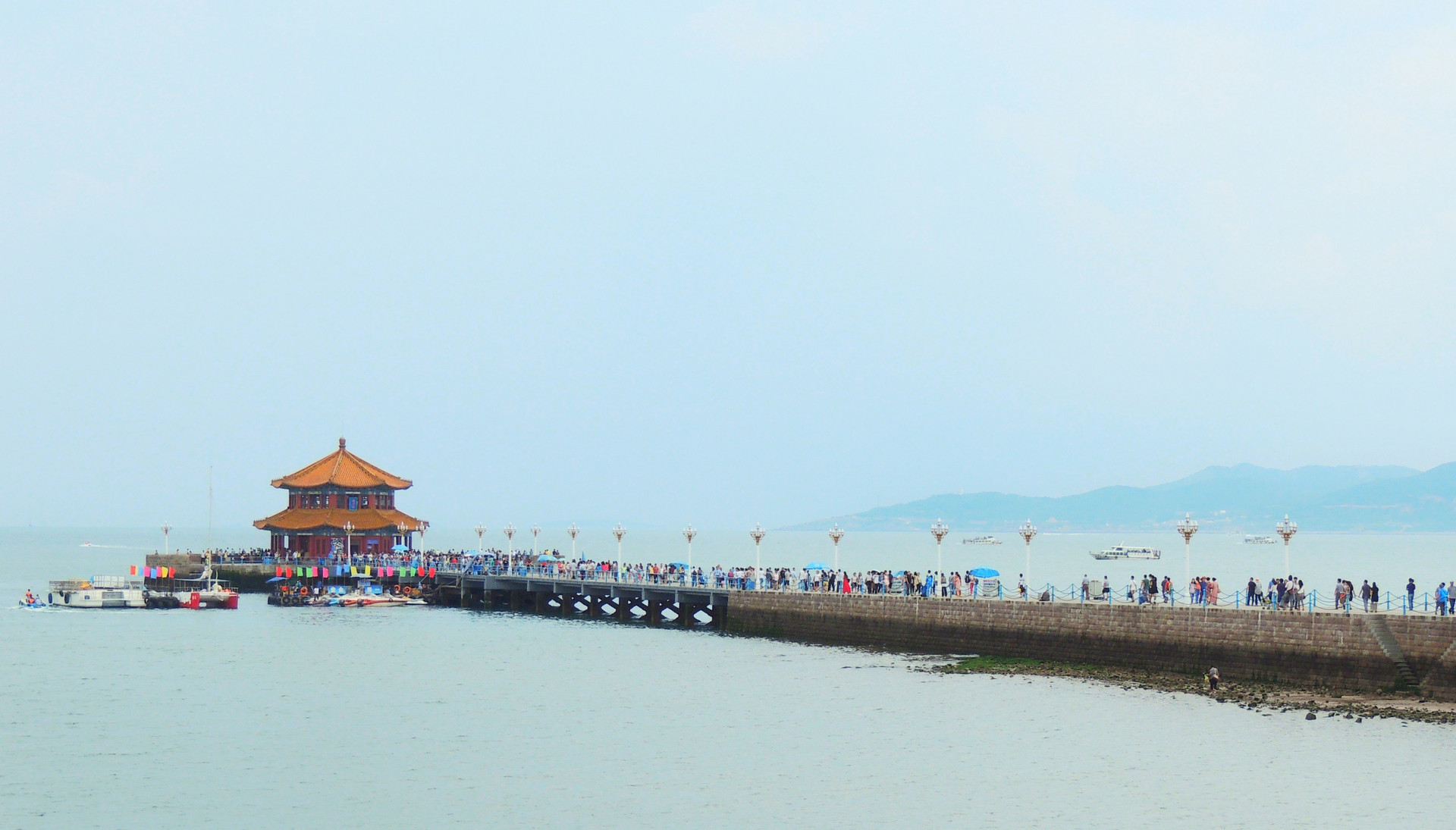 端午假期青岛栈桥景区游客云集 形成一道亮丽的风景