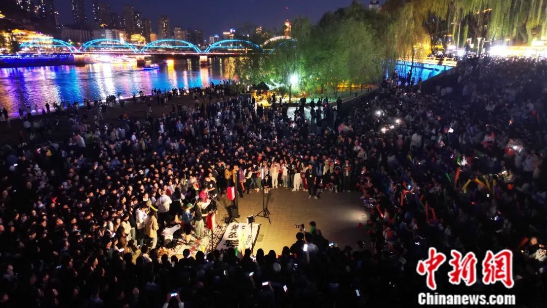 2024年4月23日晚，甘肃兰州，在黄河畔举行的路边演唱会吸引了民众前来“打卡”。图为民众在黄河边合唱(无人机照片)。九美旦增　摄