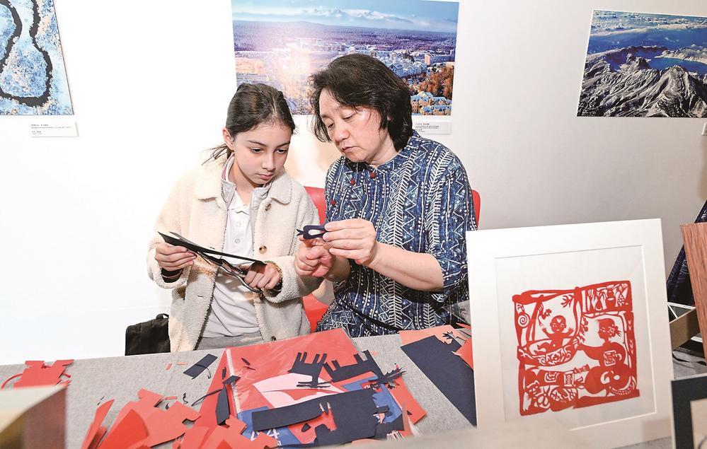 在“机遇中国·多彩吉林”文化和旅游推介交流会活动现场，法国孩子(左一)体验长白山满族剪纸。 吉林省委宣传部供图