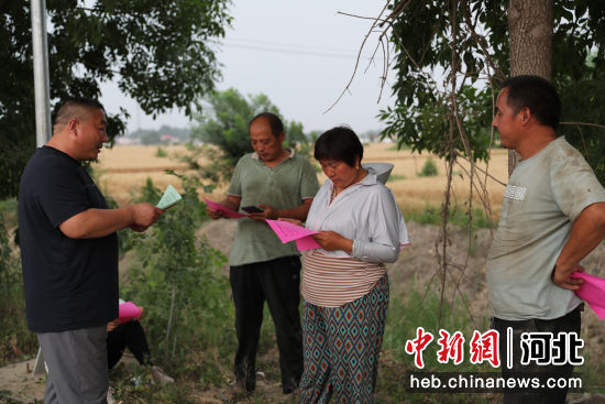 工作人员向跨区作业农机手发放安全生产资料。 赵端 摄