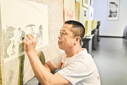 6月13日，雄安新区雄县张岗乡德韵博物馆内，拓片师何同曙正在拓印石板宴饮图。 河北日报记者 曹铮摄
