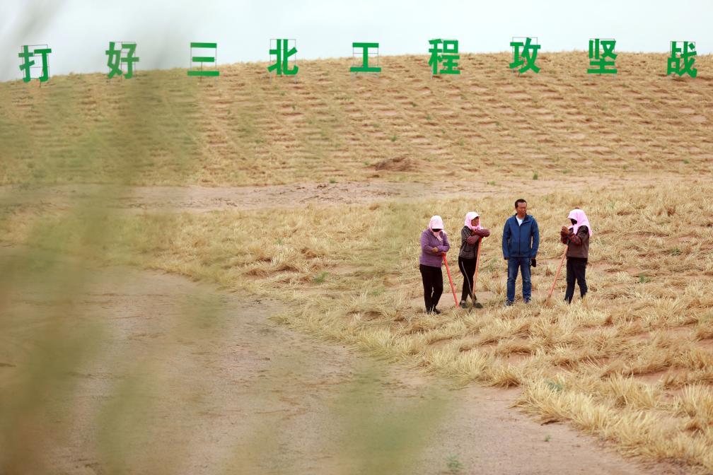 在民勤昌宁西沙窝项目现场，马俊河（左三）与当地村民交流。新华社记者　郭刚　摄