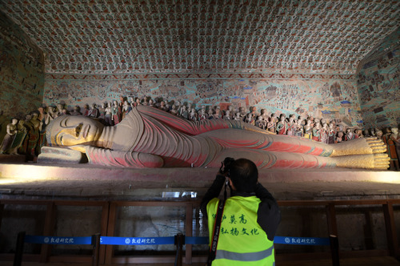 2016年10月11日，百名摄影师分组分批走进甘肃敦煌莫高窟洞窟内部进行摄影创作，领略莫高窟神韵。图为当日，摄影师在敦煌莫高窟第148窟拍摄卧佛。新华社记者　范培珅　摄