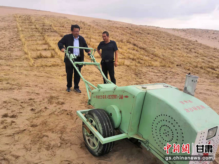 图为徐先英（左）在测试研发的草沙障压沙机（资料图）　甘肃省林业和草原局供图