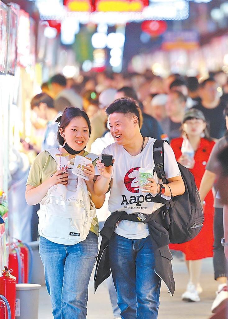 游客在夜市品尝特色美食