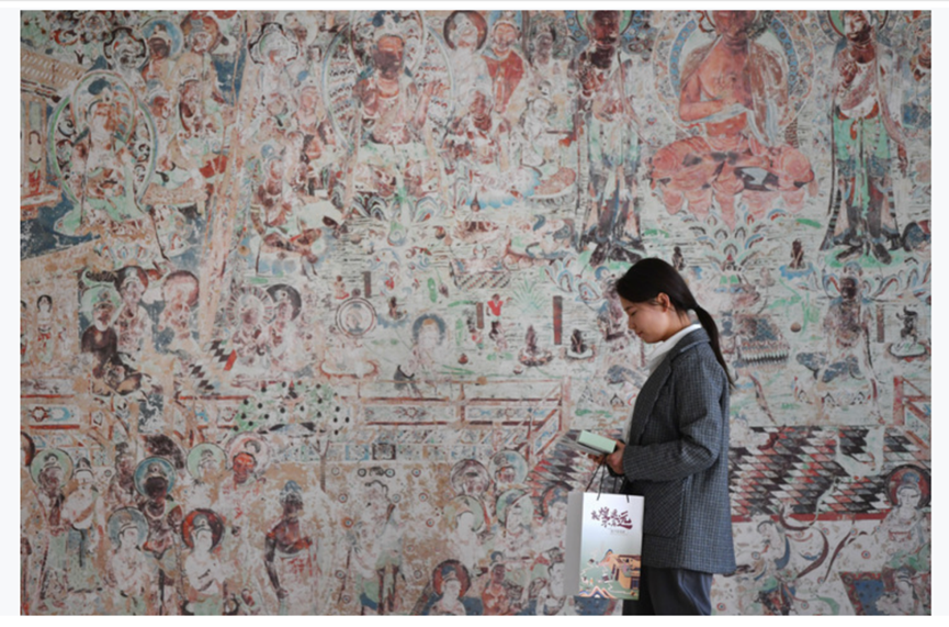 图为敦煌研究院文物数字化保护团队创意营销人员廖雪婷从一幅高保真复制壁画前走过（2023年4月25日摄）　新华社记者　陈斌　摄