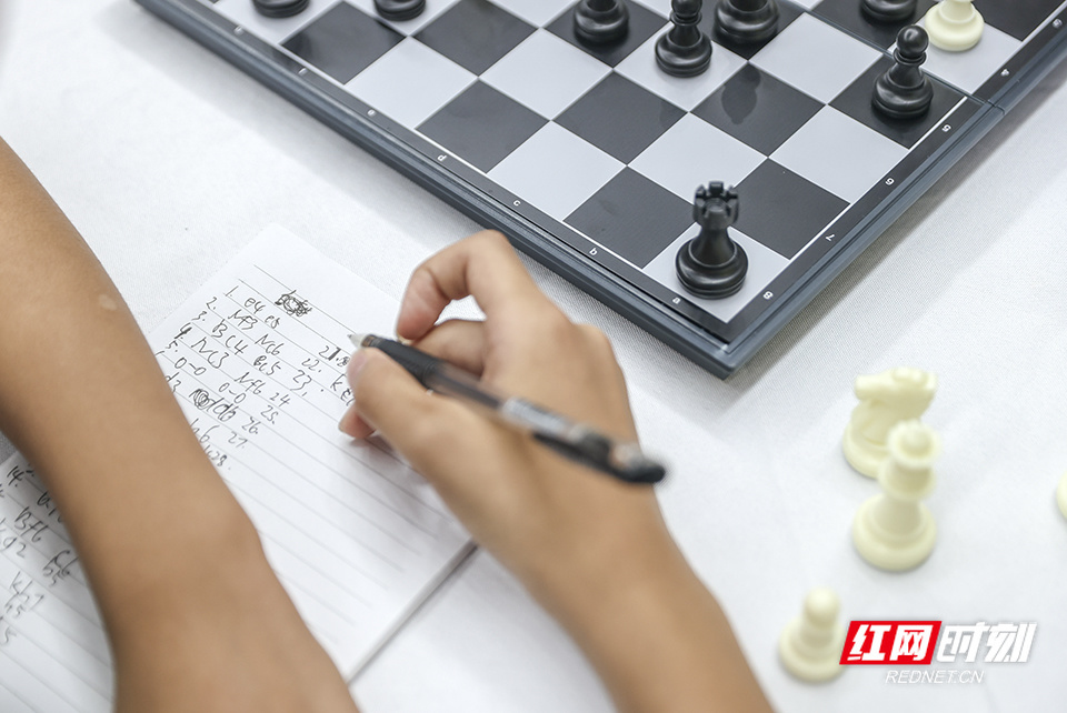 6月23日，湖南农业大学体育馆，正在比赛中的选手一边下棋，一边做好笔记。