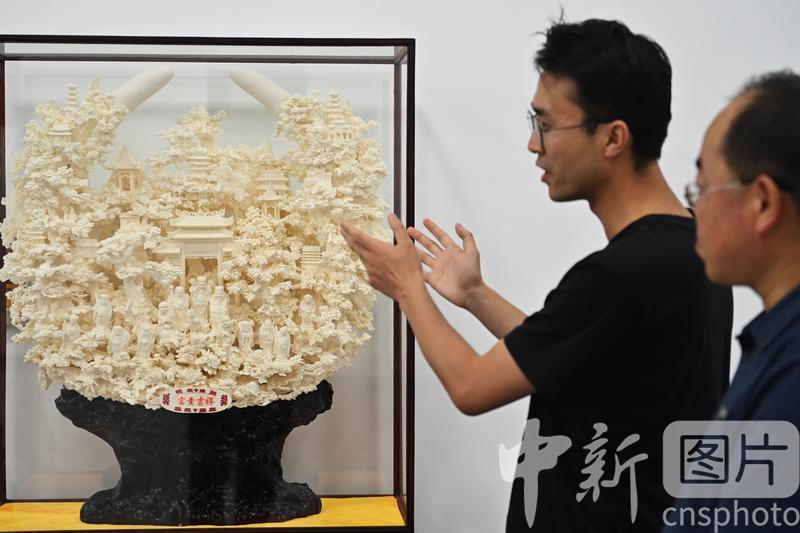 7月4日，甘肃省临夏县，游客观赏高级技师张志伟的骨雕作品《富贵吉祥》。张志伟表示，年轻时他曾从事象牙雕刻工作，现如今利用牛骨羊骨代替象牙雕刻，创作出的作品效果更好、更加丰富。当地公司以当地牛骨羊骨等为原材料进行雕刻创作，“变废为宝”，延伸了当地牛羊产业发展链条。 中新社记者　李亚龙　摄