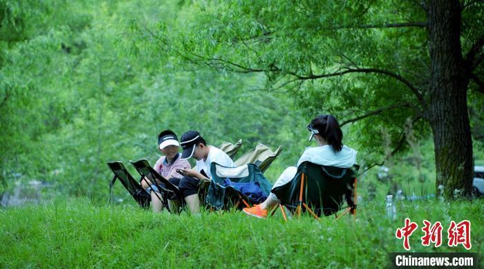 7月2日，紧邻国家4A级旅游景区“陇右名山”兴隆山的村落——兰州市榆中县新营镇八门寺村，蜿蜒向前的溪水涓涓流淌，绿树成荫、草木茂盛，一顶帐篷，一张餐桌，三五好友……随处可见来这里露营纳凉的游人，徜徉在这片“绿野仙踪”里，悠闲自在、心旷神怡。图为游人在大山里畅享绿色。张文 摄　　