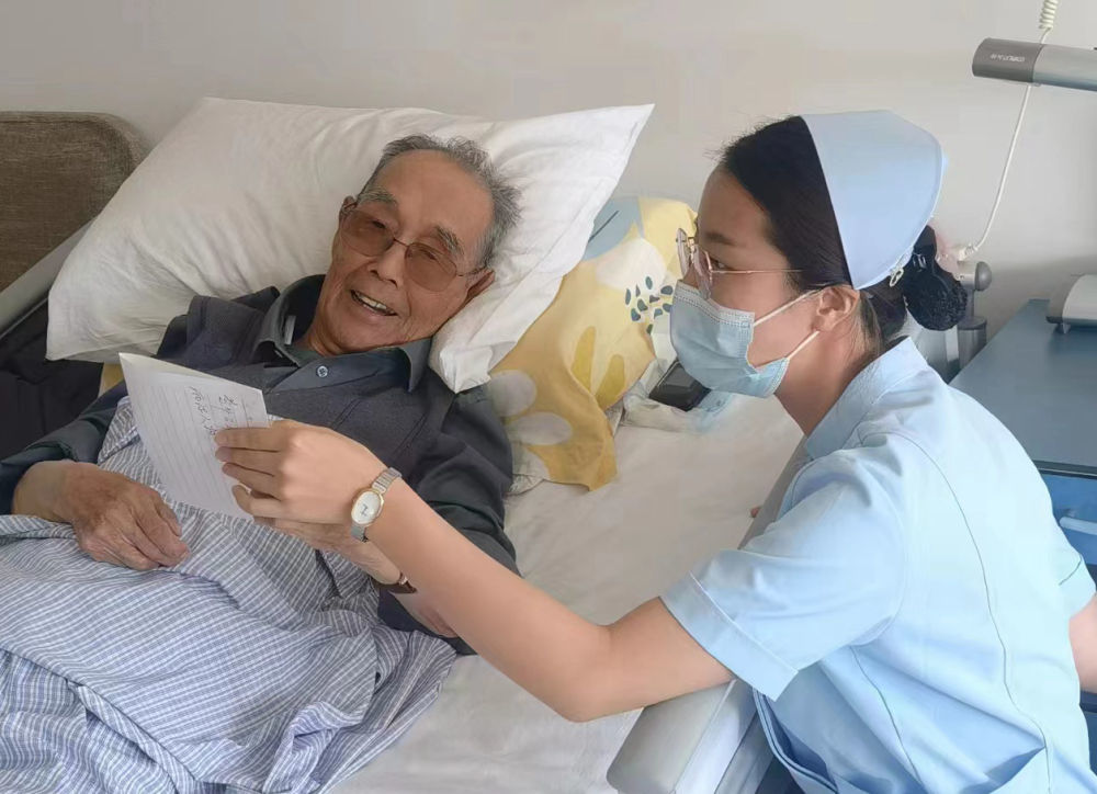 ↑2024年6月24日，老红军鲍彦章和联勤保障部队第940医院医护人员交流。新华社发（丁小涵　摄）