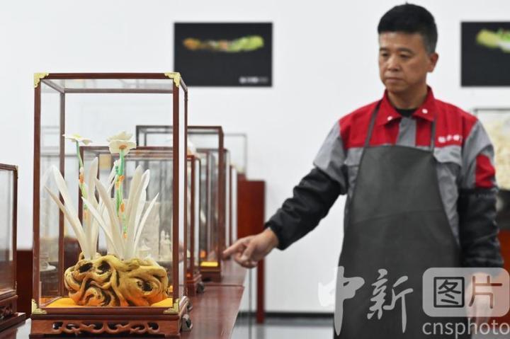7月4日，甘肃省临夏县，骨雕高级技师张志伟展示自己的骨雕作品《水仙花》。张志伟表示，年轻时他曾从事象牙雕刻工作，现如今利用牛骨羊骨代替象牙雕刻，创作出的作品效果更好、更加丰富。当地公司以当地牛骨羊骨等为原材料进行雕刻创作，“变废为宝”，延伸了当地牛羊产业发展链条。 中新社记者 李亚龙 摄