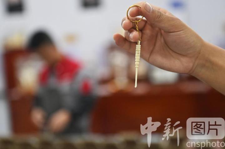 7月4日，位于甘肃省临夏县的甘肃临丰骨艺科技文化公司展厅内，游人展示骨雕制作的耳勺。该公司专业从事骨雕文化研究与技艺传承，以当地牛骨羊骨等为原材料进行雕刻创作，产品涵盖具有临夏文化符号的伴手礼、骨瓷礼、家具装饰、乐器配件、文玩把件、生活器皿等骨雕系列产品，年产各类骨雕艺术品2万多件，实现牛骨羊骨“变废为宝”，延伸了当地牛羊产业发展链条。 中新社记者 李亚龙 摄