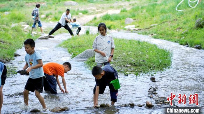 7月2日，紧邻国家4A级旅游景区“陇右名山”兴隆山的村落——兰州市榆中县新营镇八门寺村，蜿蜒向前的溪水涓涓流淌，绿树成荫、草木茂盛，一顶帐篷，一张餐桌，三五好友……随处可见来这里露营纳凉的游人，徜徉在这片“绿野仙踪”里，悠闲自在、心旷神怡。图为小孩子在溪水里嬉戏。张文 摄　　