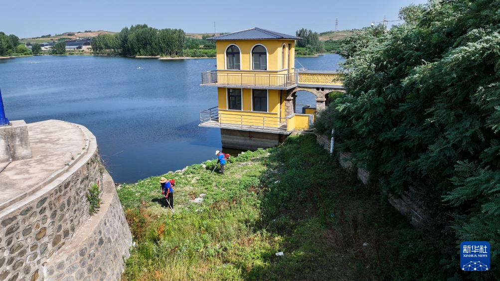 6月28日，工作人员在河北省秦皇岛市卢龙县双望镇黄家村水库清理溢洪道杂草（无人机照片）。