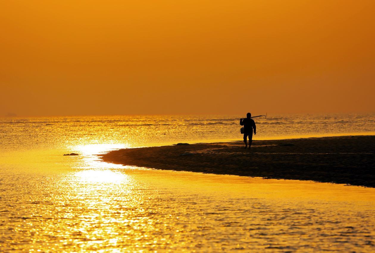 日出时分，渔民出海捕捞渔获，沙滩伴着大海安静的等待收获。安佰明 摄