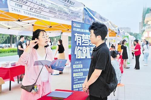 7月6日，在衡水市区爱琴海购物公园外的“人才夜市”上，大学毕业生张占德（右）与企业招聘人员交流。 本报记者 焦 磊摄