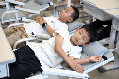 复兴大街小学暑期托管学生在躺式课桌椅上午休
