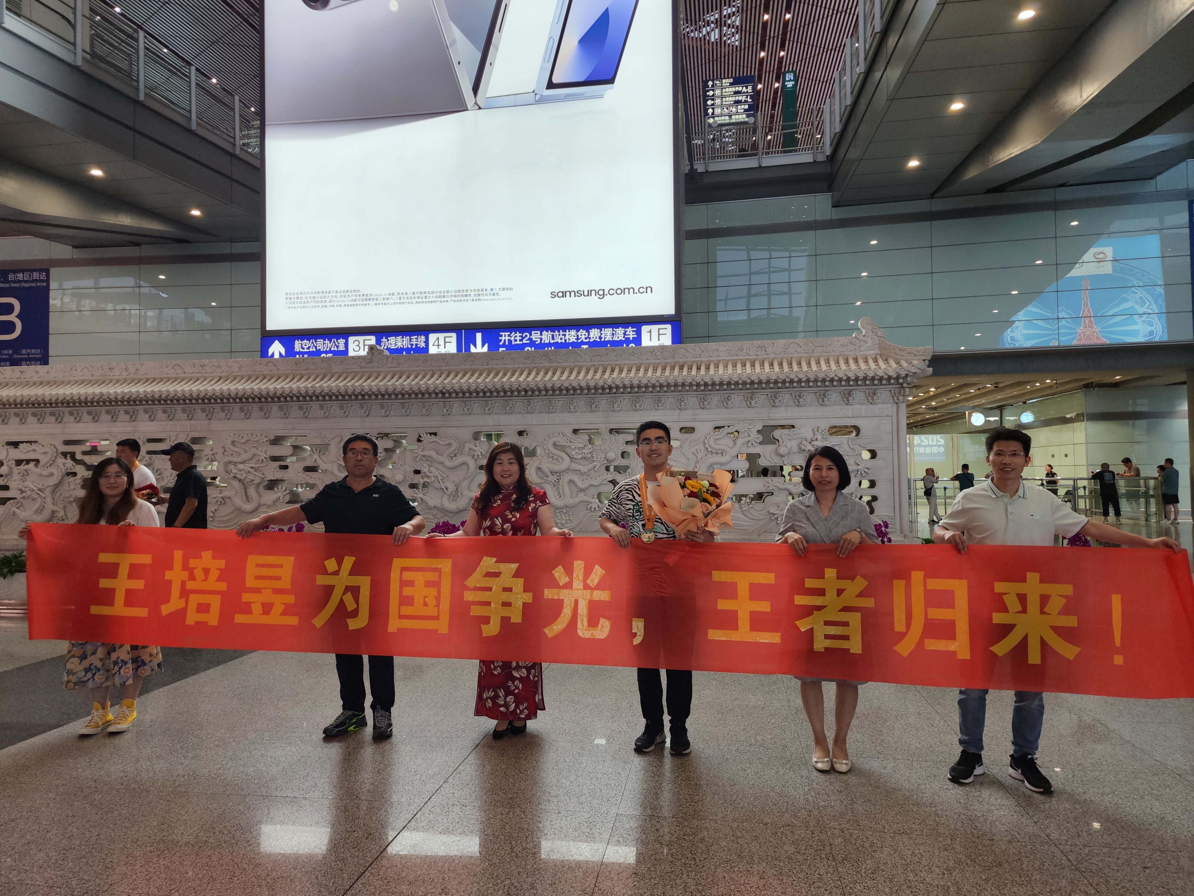 7月14日，在北京首都国际机场，家人、教练等迎接王培昱（右三）夺金归来。 朱微 摄